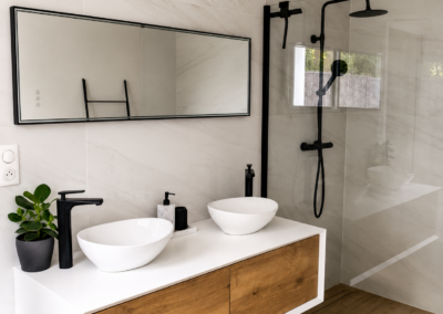 Découvrez cette rénovation de salle de bain haut de gamme réalisée par InterConstruct : double vasque suspendue, douche à l'italienne, carrelage effet marbre et robinetterie noire mat. Devis gratuit.